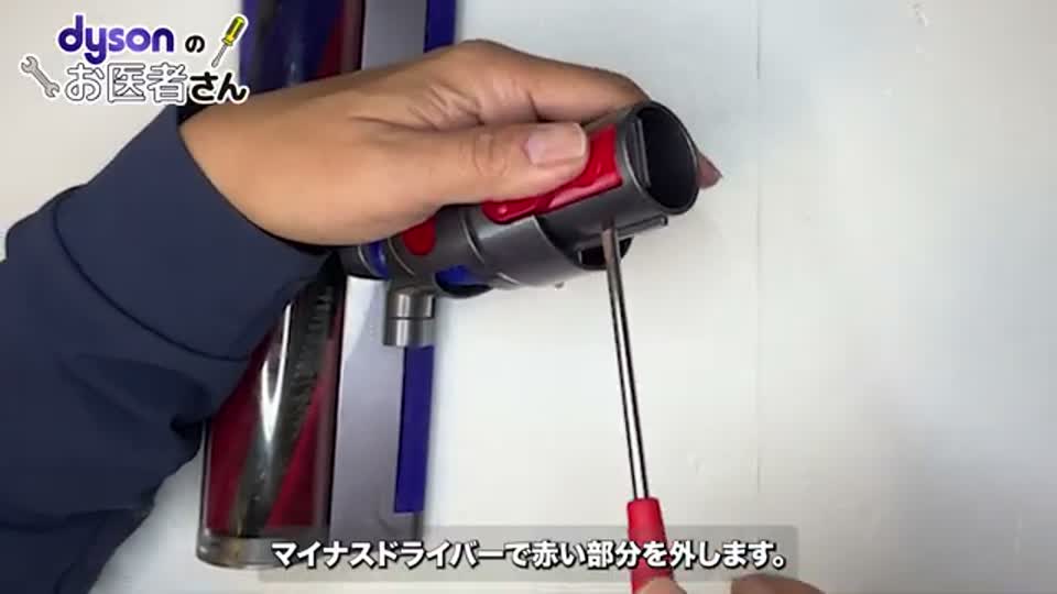 マイナスドライバーで赤いパーツを外す様子